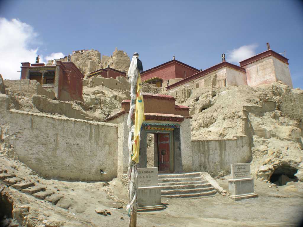 Tibet Guge 05 Tsaparang 02 Entrance Tsaparang is 21km west of Tholing (Zanda). From  left to right  are the Chapel of the Prefect, the Yamantaka Temple, the Red Temple, and the White Temple. The trail then climbs to the former residential quarters, where monks' cells were tunneled into the clay hillside. Finally, the route goes into the hillside and through tunnels before emerging in the ruins of the palace citadel at the very top of the hill, with the Demchog Temple just visible to the left. Photographing inside the buildings was strictly forbidden.